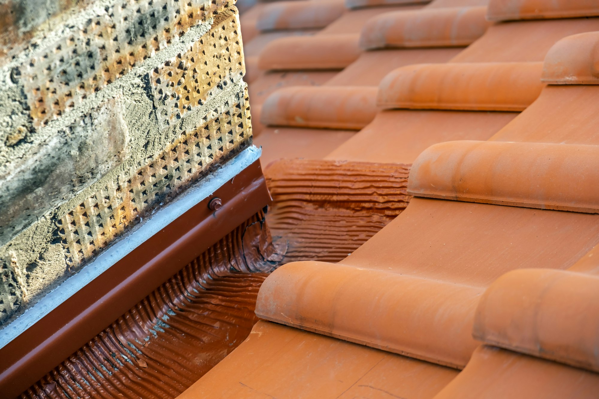 Rows of yellow ceramic roofing tiles covering residential building roof near brick chimney